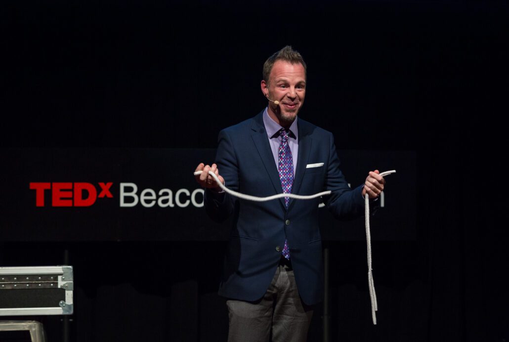 Boston-Magician-Adam-Wilber-Performing-on-stage-at-TEDx-Beacon-Street-in-Boston.